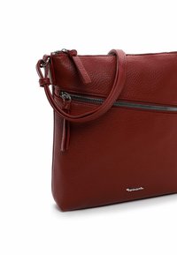 Red leather bag with a textured finish, featuring a zippered closure, adjustable strap, and a silver logo accent.