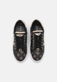 Black sneakers with gold accents, featuring a textured pattern, round toe, laces, and logo detail on the tongue and side.