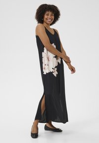 Robe maxi noire avec un imprimé floral dans des tons de rose. Comprend des fentes latérales et un décolleté en V. Tissu lisse et léger avec une silhouette fluide.