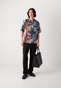 Short-sleeve shirt with a colorful abstract pattern in various shades, paired with black trousers and a black tote bag, featuring a smooth texture.