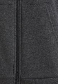 Sudadera con cremallera de color gris oscuro, con una textura suave, bolsillo tipo canguro y puños y bajo acanalados. Cuenta con un cierre central con cremallera.
