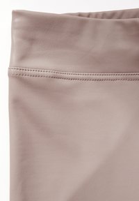 Tan nepleer stof met een gladde textuur. Kenmerkt zich door een opgerolde manchette aan de bovenkant en zichtbare stikseldetails.