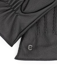 Schwarze Lederhandschuhe mit strukturiertem Material, gerafftem Design und metallischem Akzent mit Logo. Auffällige Steppnähte an den Rändern.