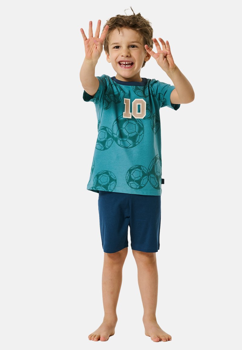 Teal T-shirt met een patroon van voetballen en "10" in beige, gecombineerd met marineblauwe shorts. Korte mouwen, zachte stof en een relaxte pasvorm.