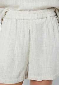 Gaiši beidzēti lina šorti ar elastīgu jostu, kuriem ir teksturēta auduma un brīvs piegriezums. Apmale ir kārtīga ar minimāli redzamām šuvēm.