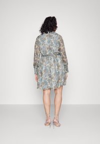 Vestido ligero con estampado en colores pastel, de mangas largas, con cintura ajustada y falda acampanada. Combinado con sandalias de tacón alto con tiras.