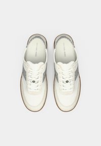 Baskets blanches et grises présentant des matériaux lisses et texturés, une forme à bout rond, un avant à lacets et un détail du logo de la marque sur la languette.