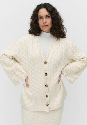 Chunky kabelgebreide cardigan in crème, met een diepe V-hals, grote knopen en brede mouwen. Ribgebreide accenten bij de manchetten en de zoom.