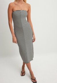 Strapless, knee-length dress made of ribbed fabric featuring black and white horizontal stripes, with a button detail down the front.