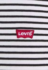 Patch logo Levi's rouge sur un fond de tissu rayé horizontal noir et blanc