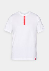 Hvid bomulds T-shirt med korte ærmer, rund halsudskæring og et rødt trykt label på forsiden med tekst og et logo i kanten.