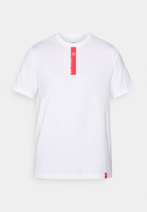Hvid bomulds T-shirt med korte ærmer, rund halsudskæring og et rødt trykt label på forsiden med tekst og et logo i kanten.