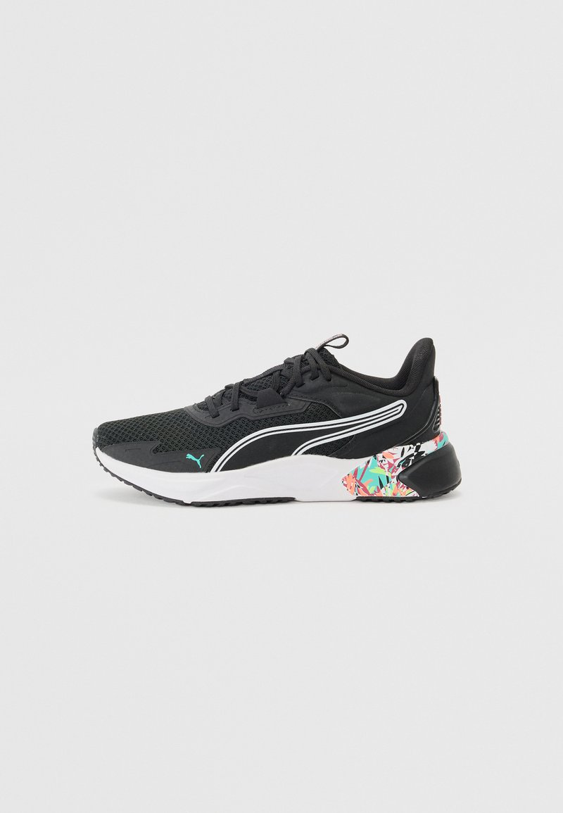 Zapatillas deportivas negras con parte superior de malla, acentos blancos y una suela con un patrón que presenta detalles en verde, rosa y azul. Logotipo de la marca deportiva visible.