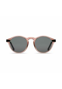 Gafas de sol redondas con un marco transparente de color rosa claro y lentes gris oscuro, con acentos negros en las patillas.