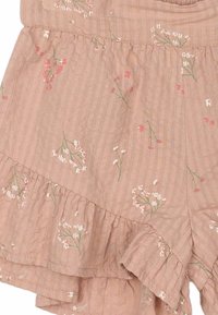 Ljusrosa shorts i texturerat tyg med blommönster. Har en volangkant, tunna ränder och små, delikata inslag av vitt och grönt.