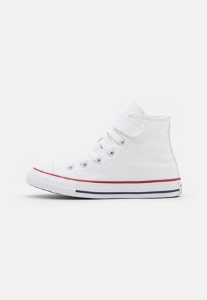 Witte hoge sneakers van canvasmateriaal. Voorzien van een klittenbandsluiting, rubberen neuskap en rode en blauwe strepen op de zool.