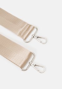 Beige stofrem med en tekstureret overflade, der har metalclips ved begge ender til fastgørelse.
