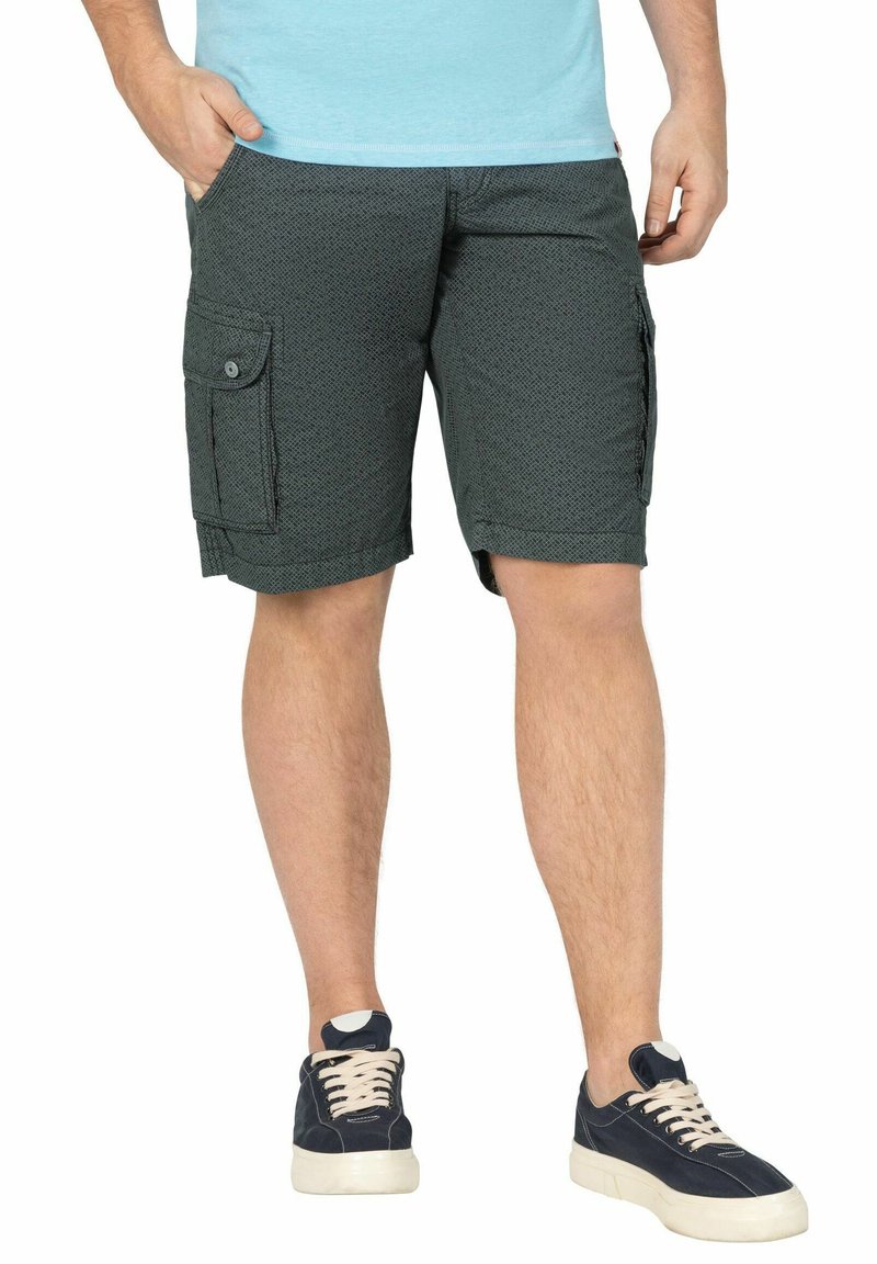 Grüne Cargo-Shorts mit einem strukturierten Muster, ausgestattet mit Seitentaschen und einem lässigen Schnitt. Kombiniert mit dunklen Turnschuhen und einem hellblauen Hemd.