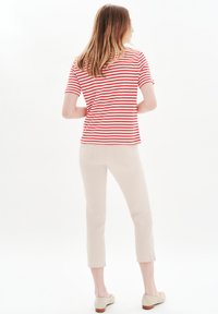 Rood en wit gestreepte top met korte mouwen, in combinatie met beige cropped broeken. Zachte stof, losse pasvorm, eenvoudig ontwerp, enkellang met zijslits.