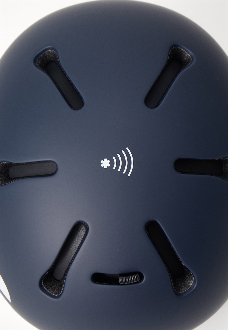 Marineblaue Helm mit Belüftungsöffnungen und einem zentralen weißen Logo. Glatte, matte Oberfläche mit strukturiertem Innenfutter und verstellbarem Riemen.