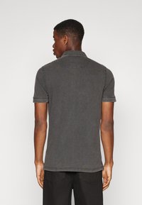 Polo gris con un cuello clásico, mangas cortas y detalles de costura sutiles, hecho de una mezcla de algodón.