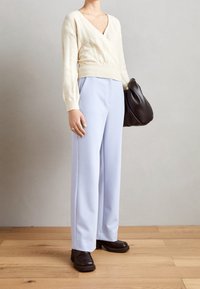 Kermanvärinen kaarrokevillapaita, vaaleansiniset leveälahkeiset housut ja musta nahkalaukku. Yksinkertainen muotoilu, pehmeä materiaali ja neutraali väripaletti.