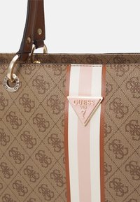 Ruda raštuota pirkinių rankinė su blizgiu akcentu, turinti auksinį logotipą, šviesiai rožines ir baltas juostas bei rudus odinius rankenėles.