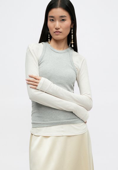 Top ligero de manga larga con un cuerpo acanalado gris y mangas crema. Textura suave; diseño ajustado con escote redondo.