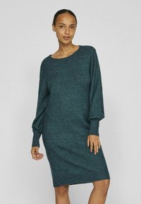 Abito a maglia color teal con vestibilità morbida, scollo rotondo e maniche lunghe e voluminose. Tessuto morbido con polsini e orlo a costine.