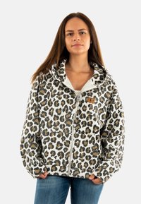 Haut zippé en imprimé léopard avec une grande capuche doublée douce, des poches avant et un design contrasté beige et noir sur fond blanc.