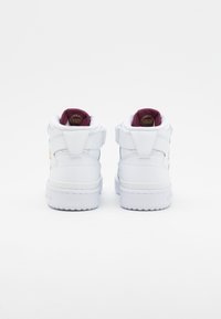 Vita högsko och sneakers med en läderöverdel, vadderad krage och vinröd inredning. Utrustad med justerbara remmar och en strukturerad gummisula.