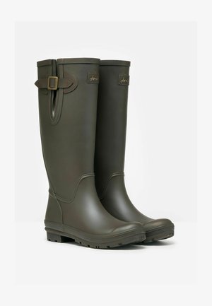 Vihreät kumisaappaat kiiltävällä pinnalla, sivussa solk detay ja rakenteelliset pohjat vetolujuuden vuoksi. Suunnittelussa on pyöristetty kärki ja sileä yläosa.