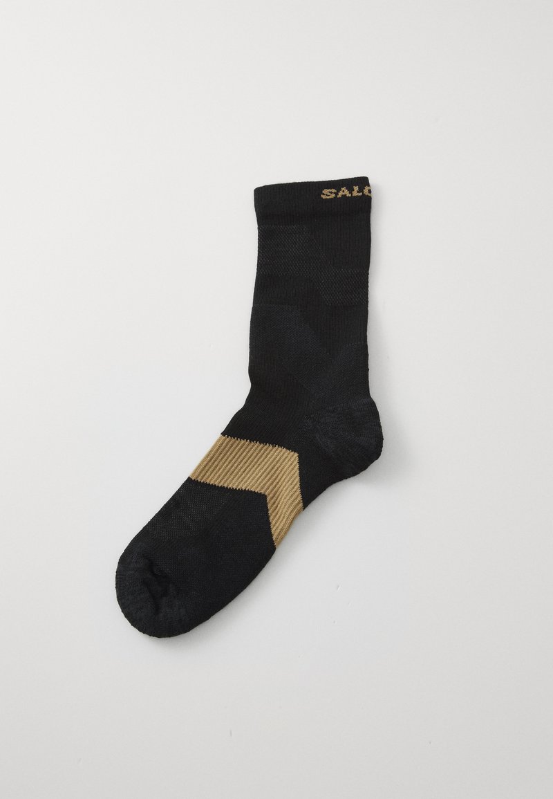 Meia preta com um padrão geométrico apresentando um design em zigzag khaki em contraste no tornozelo e textura canelada na parte superior.