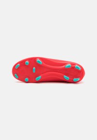Sole di scarpa da ginnastica rossa con un design testurizzato, caratterizzata da accenti blu e vari tacchi di trazione per una presa migliore.
