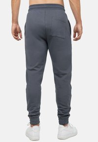 Grijze sweatpants met een geribbelde tailleband, zijzakken en een achterzak. Boorden bij de enkels. Draag ze met witte sneakers.