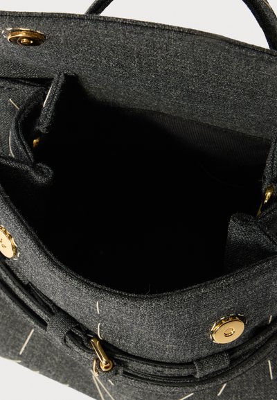 Bolsa de tecido preta com acabamentos em dourado, apresentando um interior sem compartimentos visíveis. Superfície texturizada e costura em contraste.