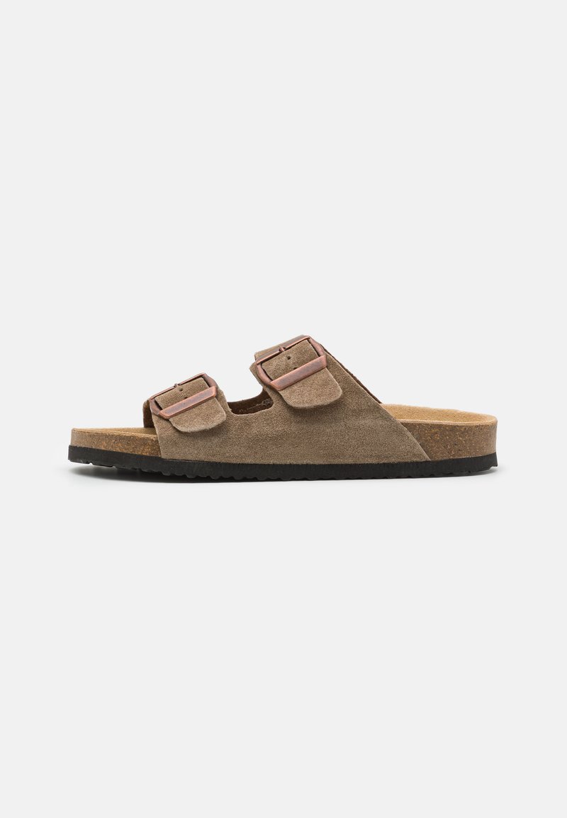 Sandal slide in camoscio marrone con due cinturini regolabili, fibbie metalliche e una soletta in sughero. Suola in gomma per una buona aderenza.