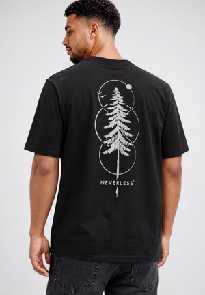 Man wearing black t-shirt with white graphic of tall pine tree, three overlapping circles, two birds, and word "NEVERLESS" on back.