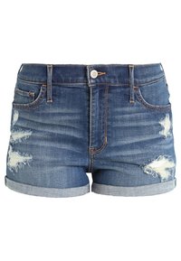 Pantalones cortos de mezclilla en un lavado azul medio con dobladillos deshilachados, detalles desgastados, diseño de cinco bolsillos y cierre frontal con botón.