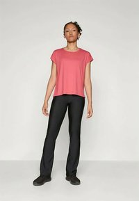Pink short-sleeve top with a loose fit, paired with black pants and dark shoes. Simple design and smooth fabric texture.
