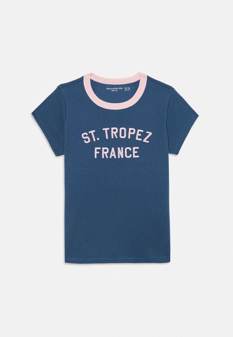 Mørkeblå t-skjorte med kort erme og en rosa ribbet halslinning, med teksten "ST. TROPEZ FRANCE" trykt i lys rosa over forsiden. Laget av bomull.