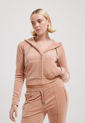 Geknipte zip-up hoodie van zachte, blush fluweel met een kangoeroezak en een verstelbare capuchon. Gepaard met bijpassende fluwelen joggers.