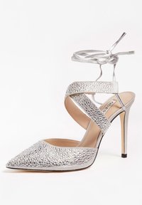 Chaussure à talon aiguille argentée avec un bout pointu, ornée de strass, dotée de brides entrecroisées et d'un délicat enroulement autour de la cheville pour le soutien.