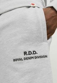 Light gray sweatshirt with R.D.D. and Royal Denim Division embroidered in black. Features a red tab label and soft texture.