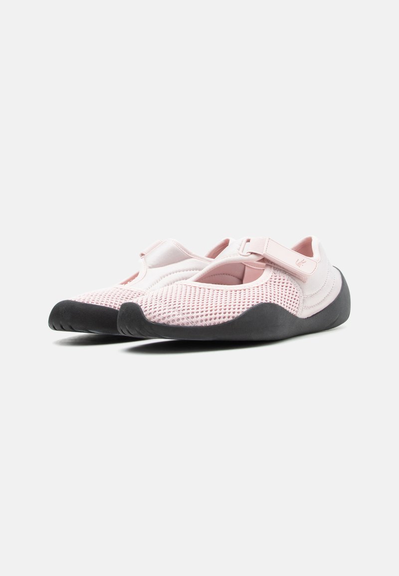 Sneakers in mesh rosa chiaro con suole nere, dotate di chiusura a strappo e design con punta arrotondata, mostrate da una vista frontale angolata.