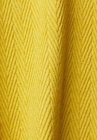 Tissu jaune avec un motif discret en chevrons et de doux plis créant texture et profondeur.