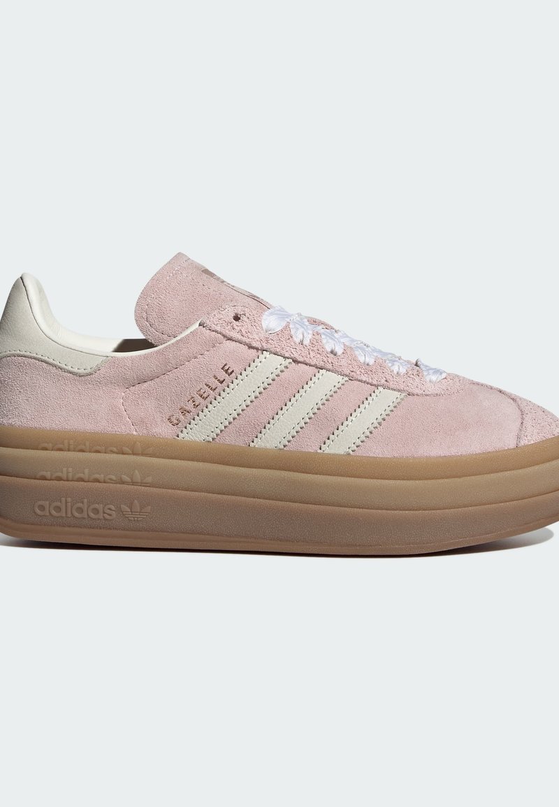 Roze suède sneakers met een beige accent en drie witte strepen. Voorzien van een dikke bruine rubberen buitenzool en witte veters. Klassiek ontwerp.