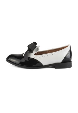 Chaussure plate en cuir noir et blanc avec une finition brillante, présentant un bout rond, un nœud décoratif et des détails perforés sur le côté.