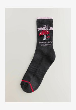 Donkergrijze sok met een roze bovenband, voorzien van een rode paddenstoelafbeelding en de tekst "DE PADDENSTOEL Natures tiny umbrella" in het roze.