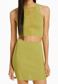 Žlutozelená dvoudílná souprava s ribbed texturou, bezramenný crop top s výřezem a odpovídající sukně se bočními rozparky.